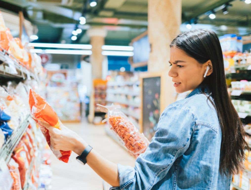 Dissatisfied young woman wearing casual outfit and earphones (Sticker Shock: The Priciest Grocery Goodies of the Aisles)