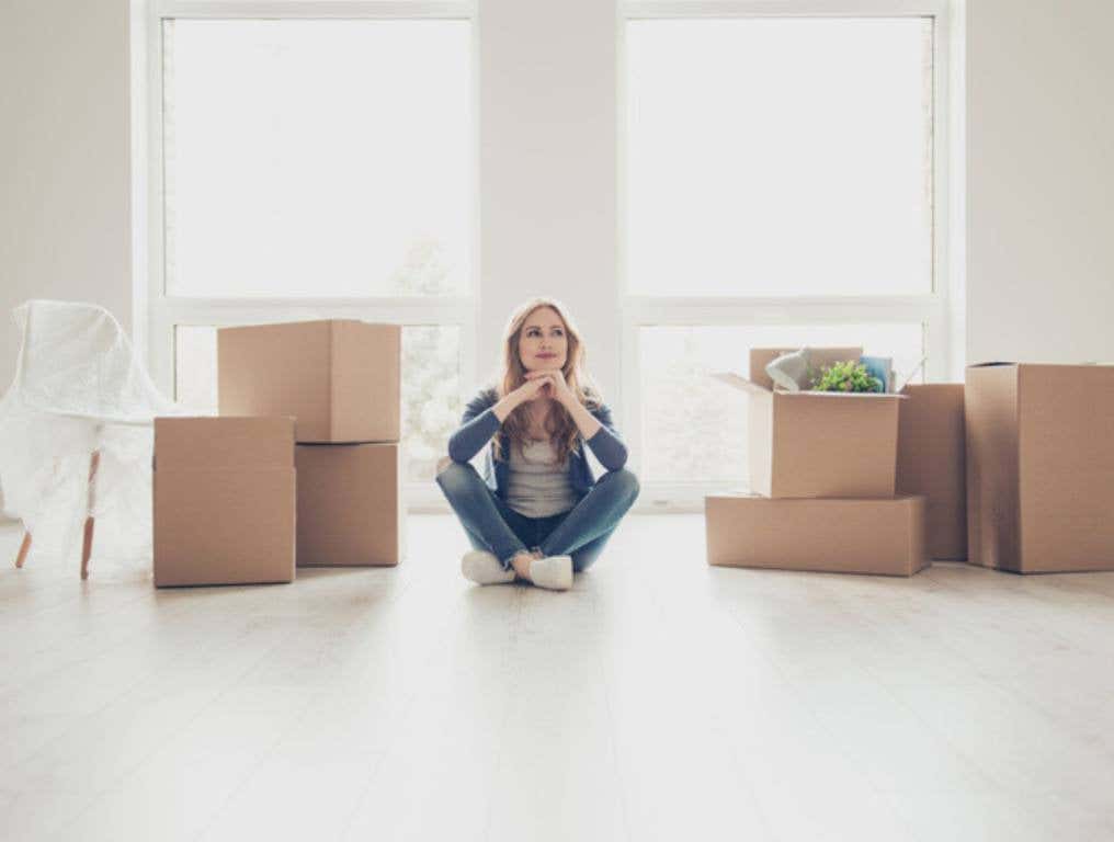 woman sitting on the floor and thinking how to unpack all the stuff surrounded by boxes (New Jersey's Best and Worst Cities For Women)