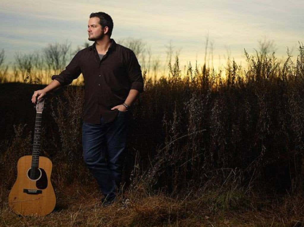 Eagles song performer Kenny Curcio with a guitar in a field