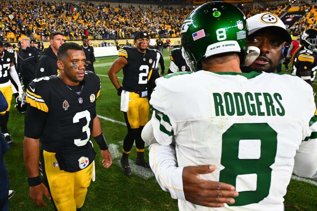 Aaron Rodgers (R) hugs Steelers coach Mike Tomlin while Justin Fields (background #2) watches.