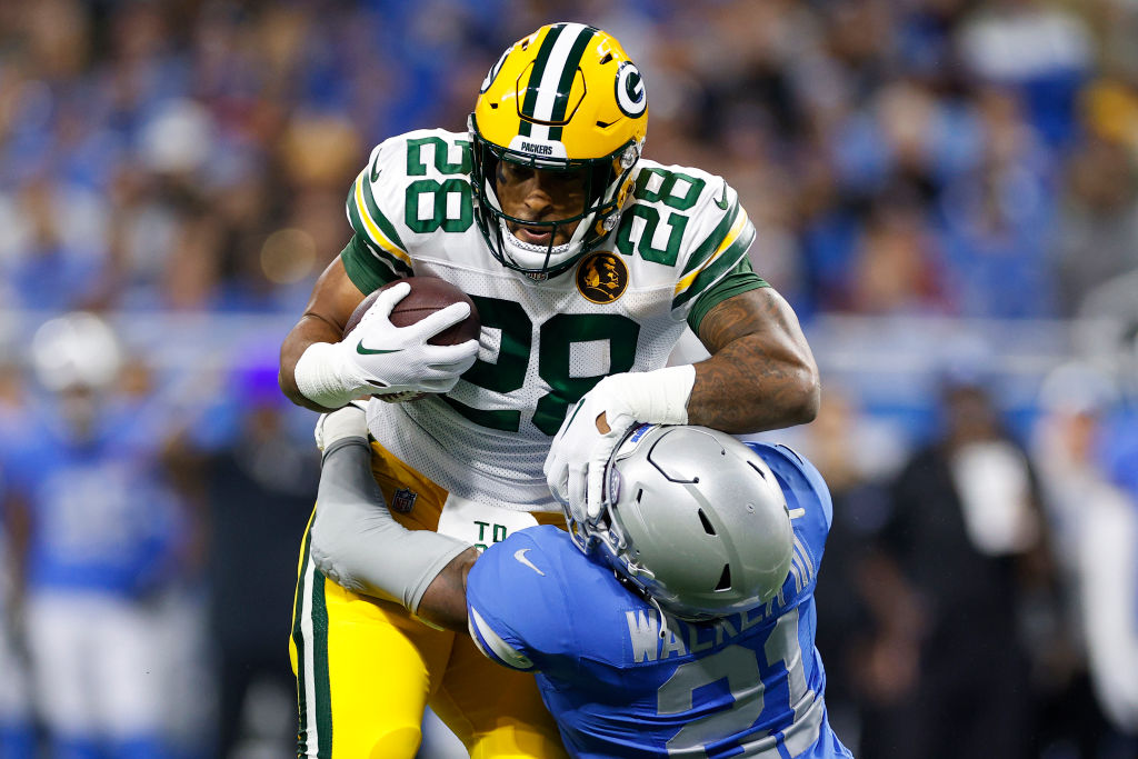 AJ Dillon stiff-arms past a Detroit Lions defender. 